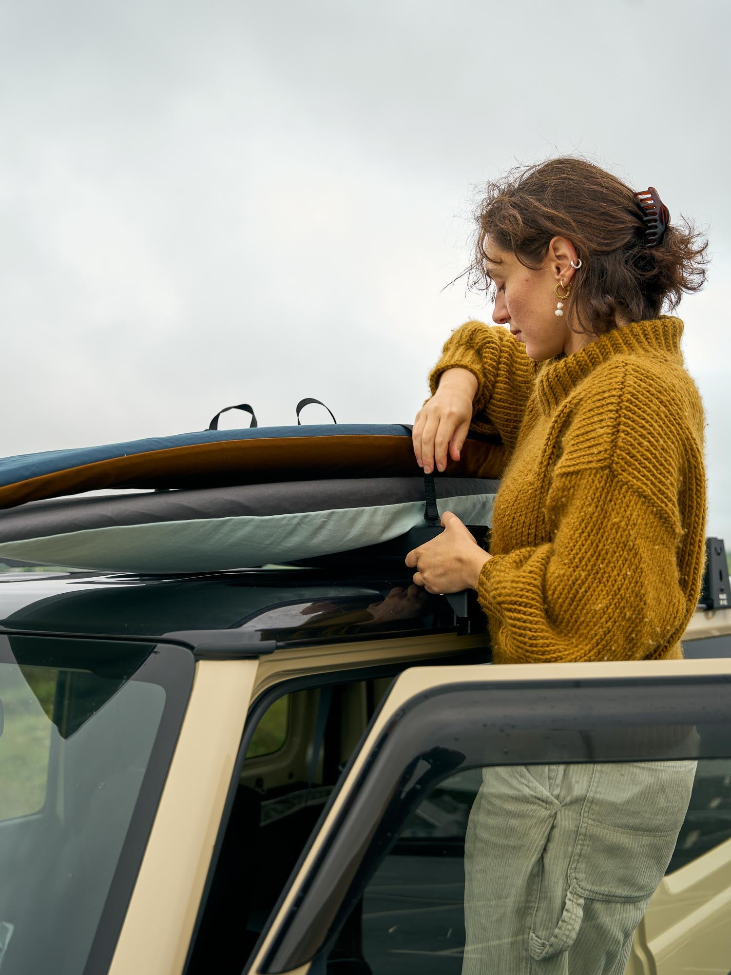 Person taking surfboards in board covers off the roof of a car.
