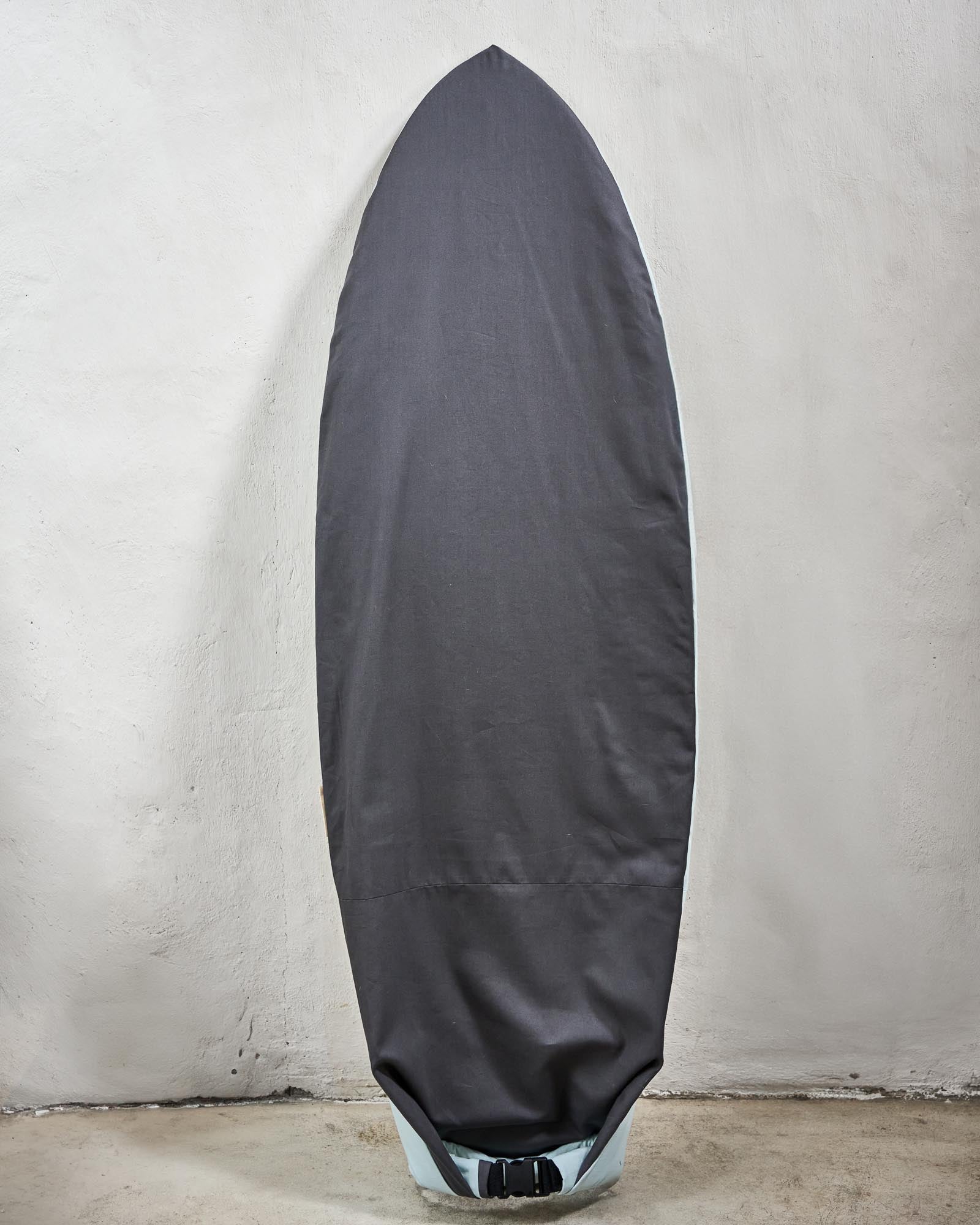 Handmade grey surfboard cover on a fish against a grey wall.