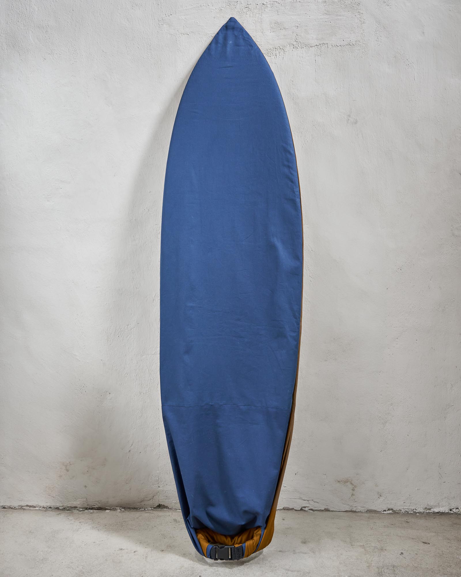 Handmade blue surfboard cover on a shortboard against a grey wall.