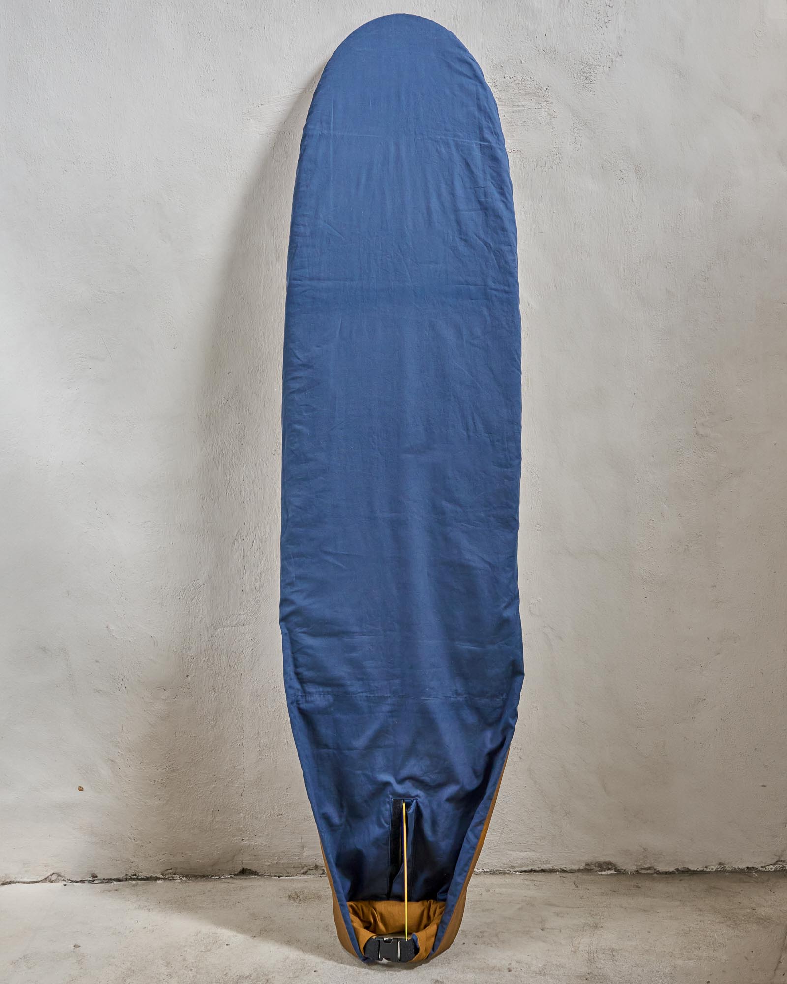 Handmade blue surfboard cover on a longboard against a grey wall.
